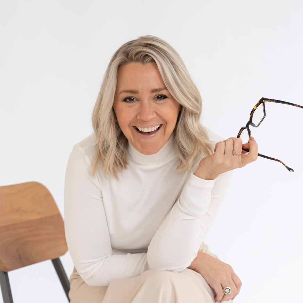 headshot of meghan doll holding glasses laughing