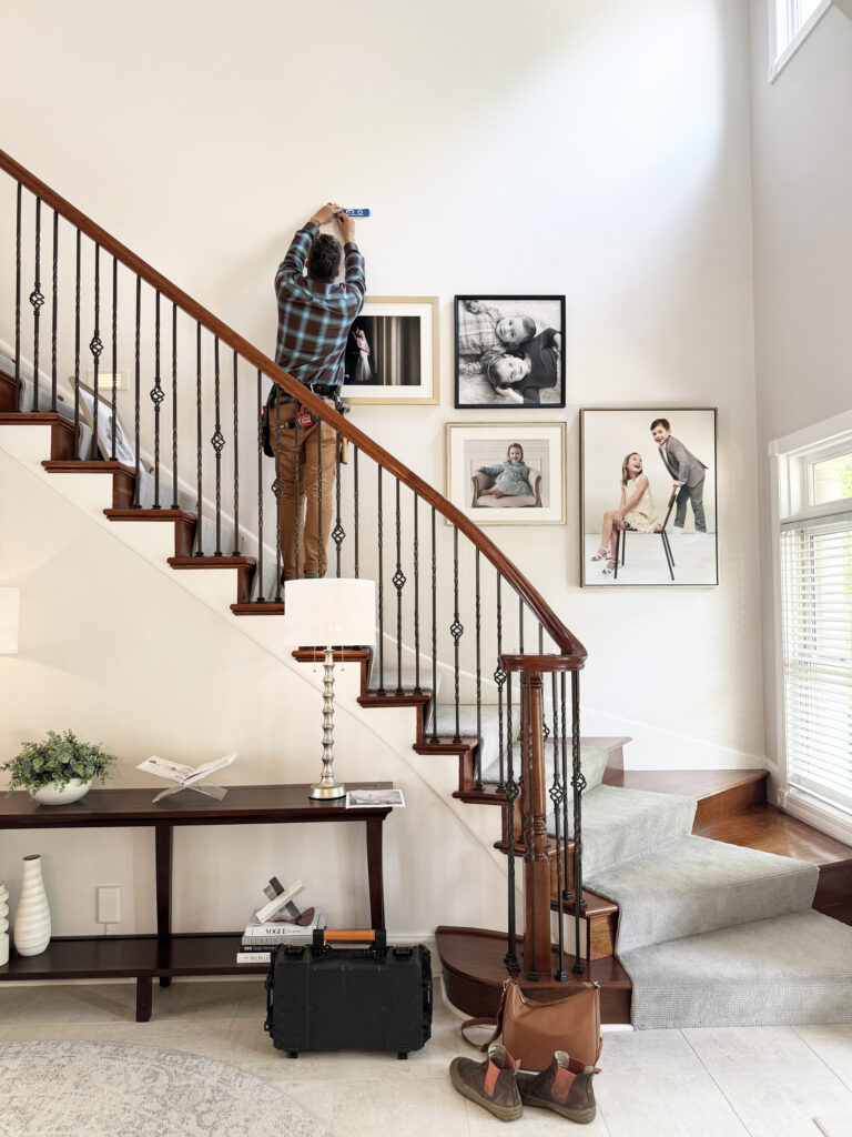 Meghan Doll Photography Artwork being hung on staircase of nice home in shorewood, MN