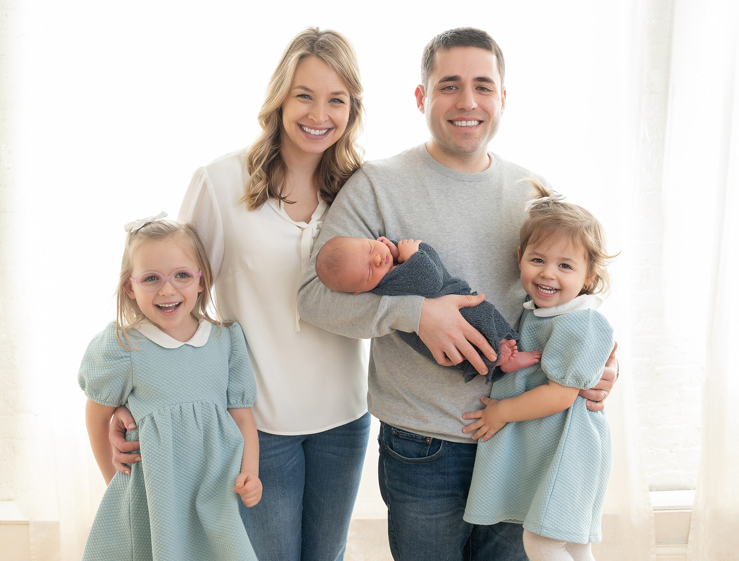 Family of five with two little girls in matching dresses and a little newborn baby.