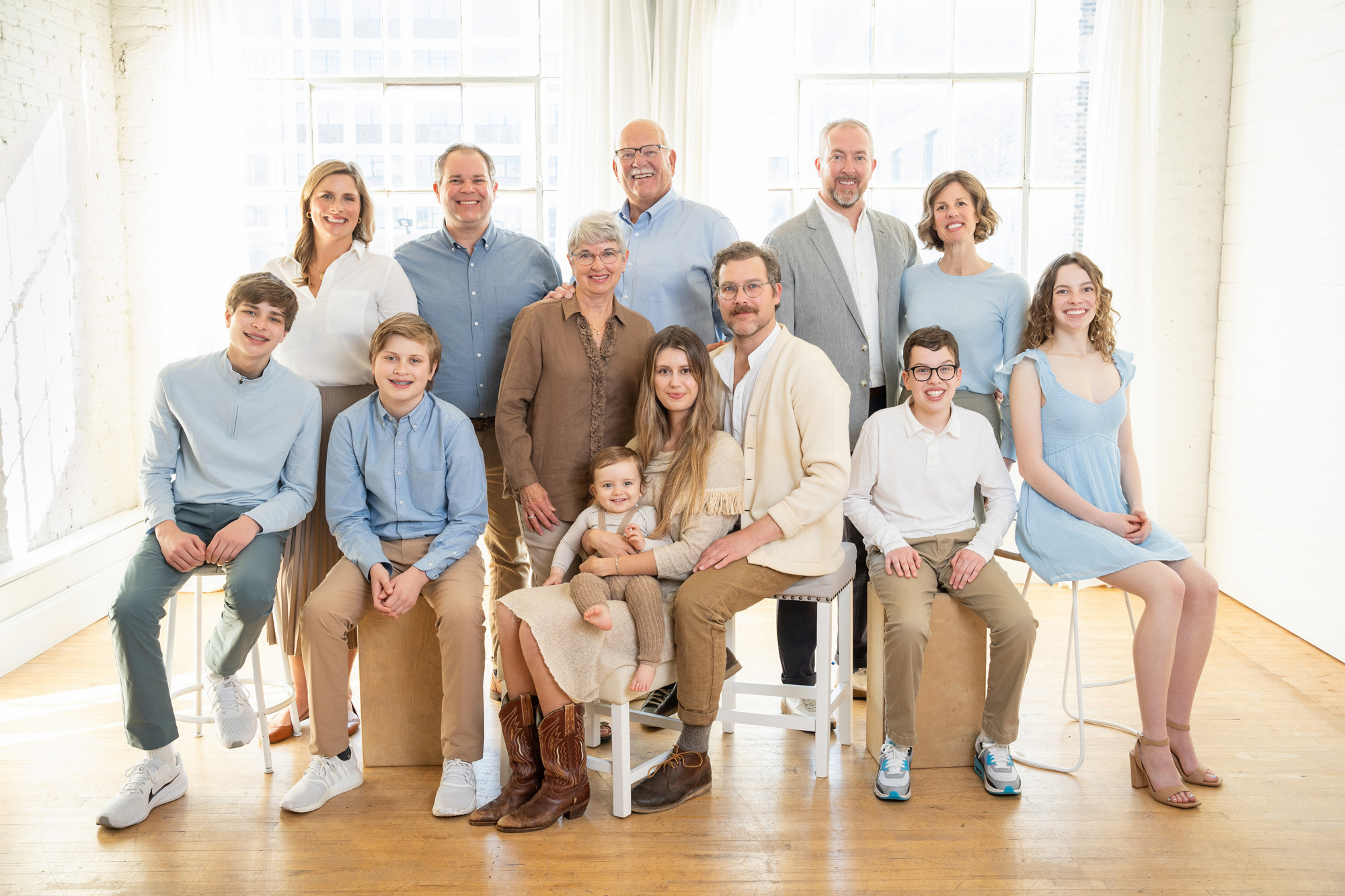 Large extended family wearing blue and neutral tone clothing.